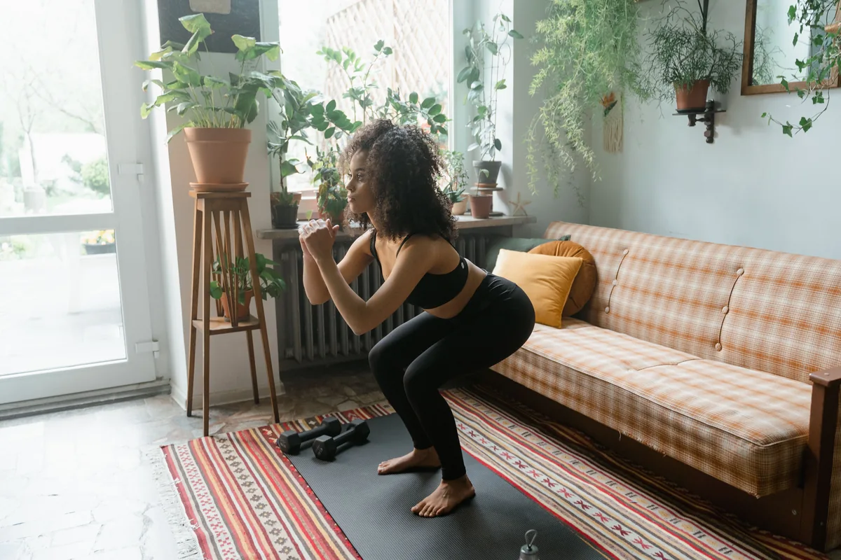 Woman doing bodyweight squats in a bright living room with plants