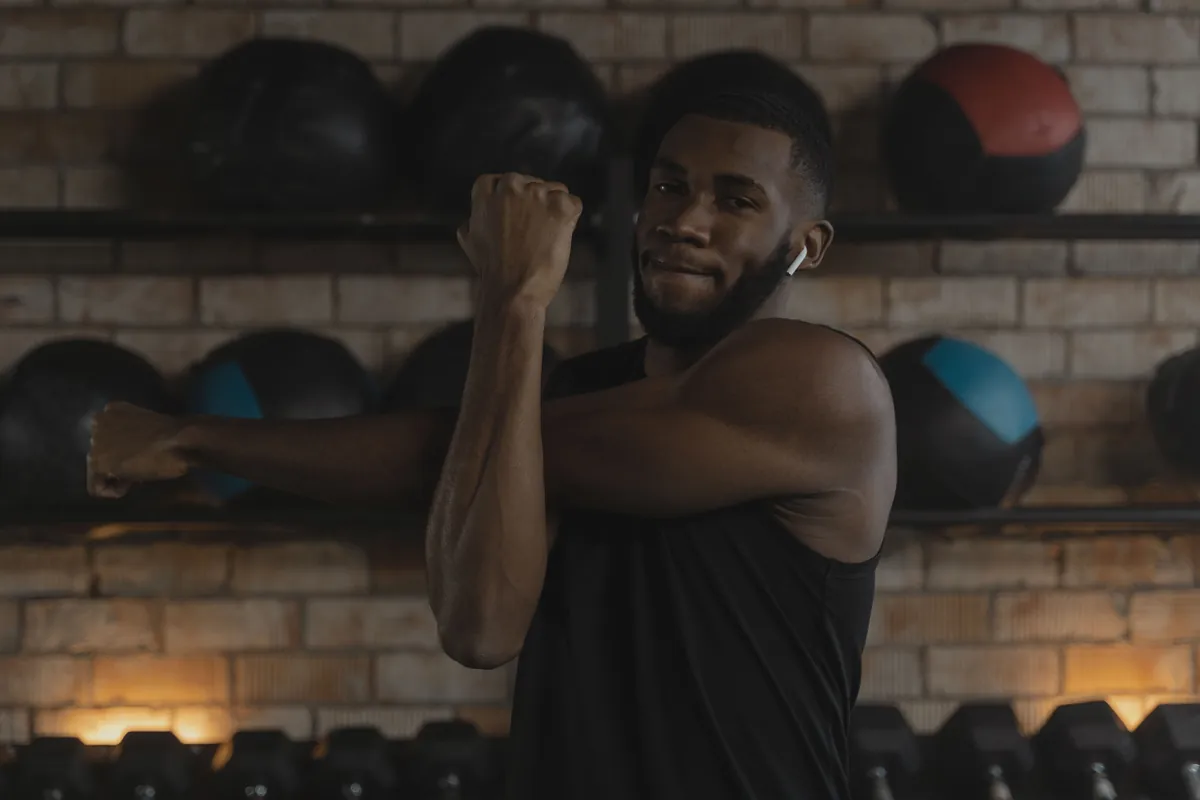 Man performing a dynamic shoulder and arm stretch as a warm-up in a gym before training