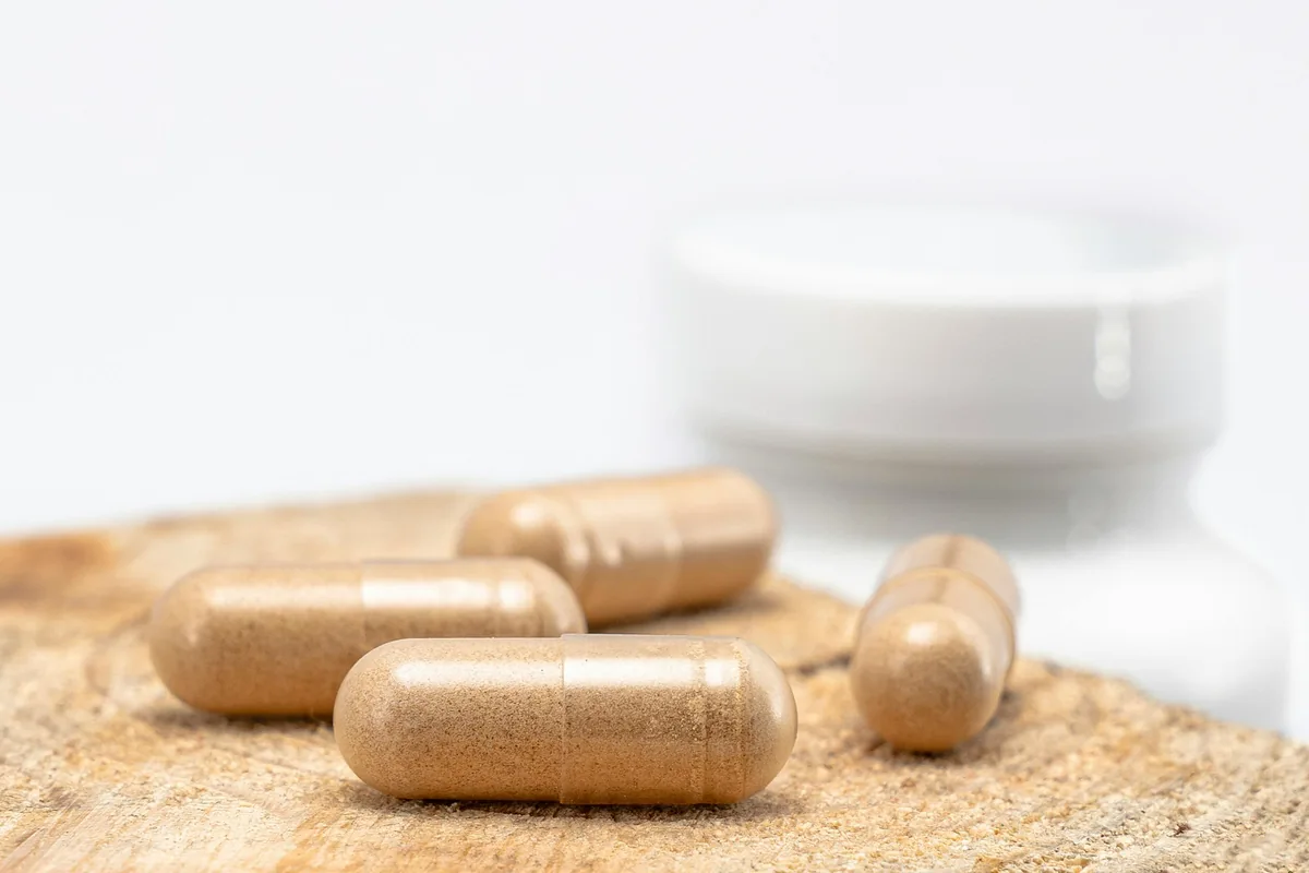Natural probiotic supplement capsules on a wooden surface
