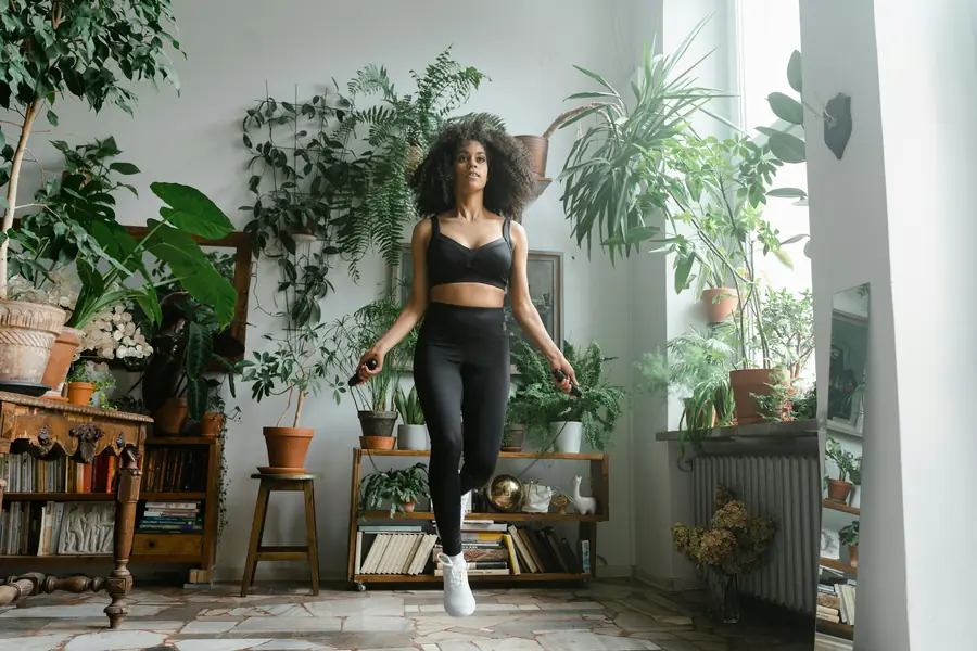 Woman jumping rope indoors surrounded by plants