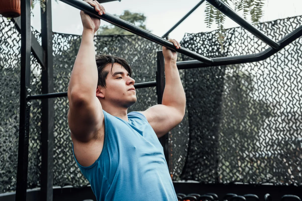 Man performing a pull-up on an outdoor bar