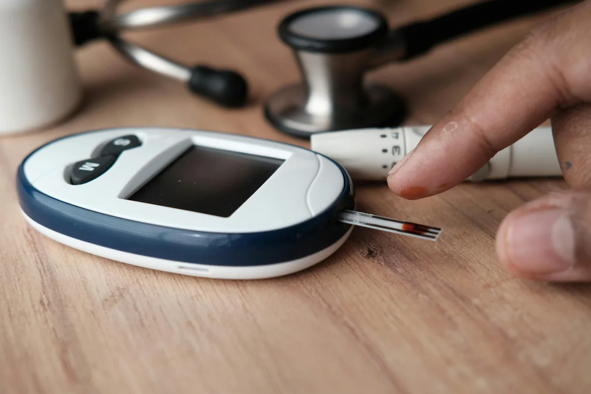 Glucose meter and lancet on a wooden surface with a stethoscope
