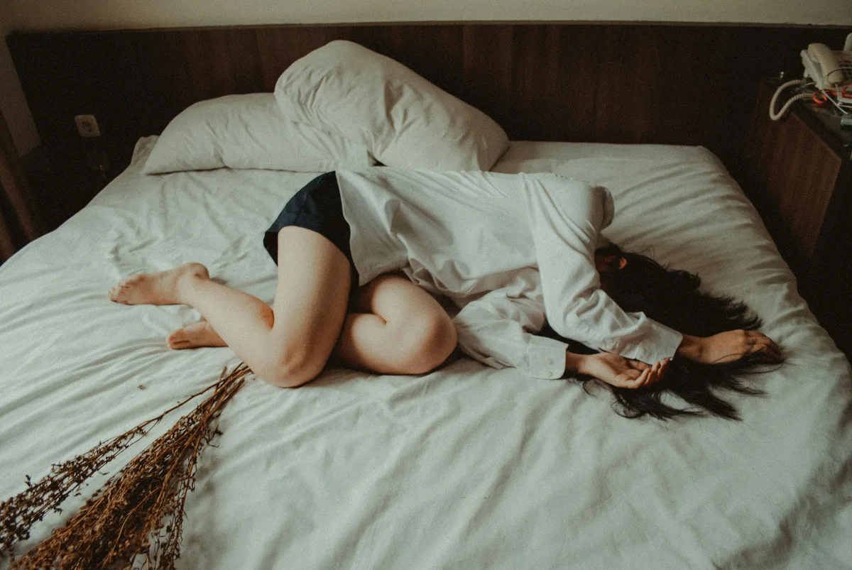 Woman lying exhausted in bed, representing the fatigue of iron deficiency without anemia