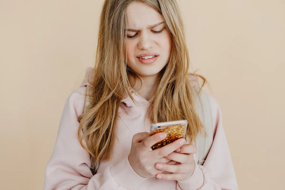 Teenage girl looking at social media on phone with visible distress, social comparison concept