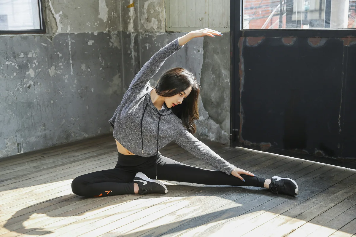 Woman performing an active lateral stretch on the floor with full control and range of motion