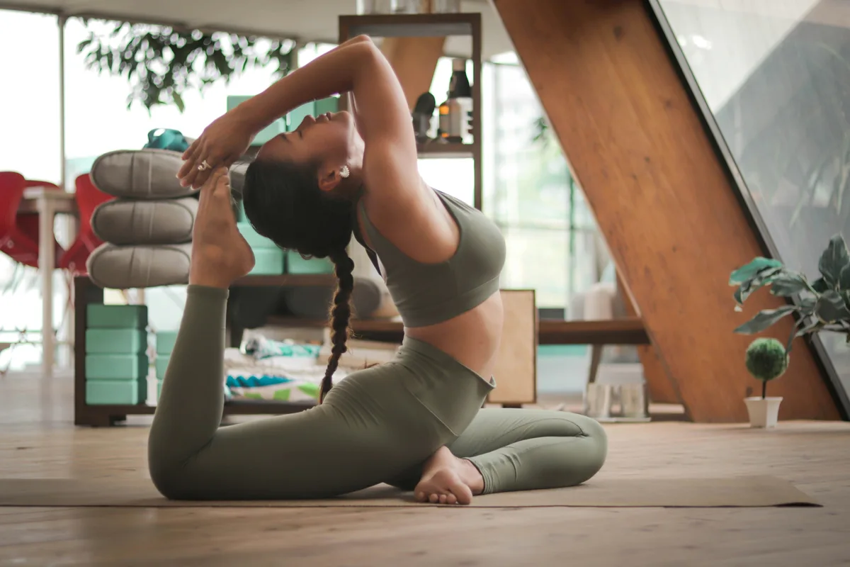 Woman performing a deep yoga backbend on a mat at home, demonstrating advanced spinal mobility